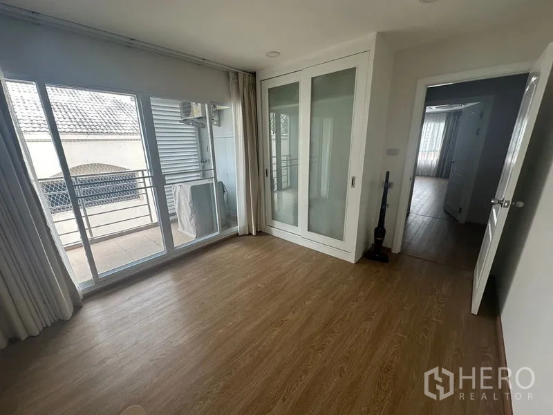 Condominium for rent - Bedroom corner with built-in glass wardrobe and balcony rail outside.