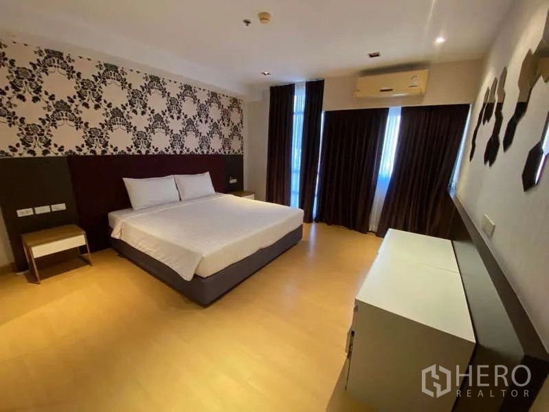 公寓 出租在Khlong Toei, Bangkok - 主卧配特大床，花纹壁纸、遮光窗帘、木地板与空调。