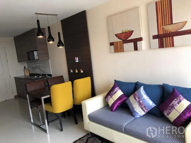 คอนโด ให้เช่าในKhlong Toei, Bangkok - พื้นที่นั่งเล่นและรับประทานอาหารแบบโอเพ่นแปลน มีโซฟา หมอนอิงสีสัน โคมไฟแขวน และครัวขนาดกะทัดรัด