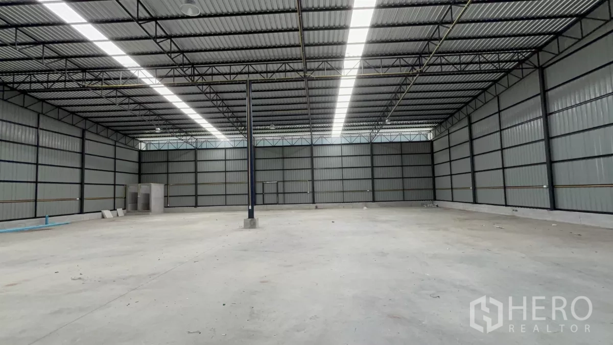 Warehouse for rent in Khlong Toei, Bangkok - Panoramic view of empty warehouse with bright roof skylights and ample loading area.