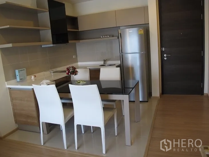 公寓 出租或出售在Khlong Toei, Bangkok - L形厨房配餐桌与不锈钢冰箱，紧邻入户门。