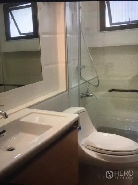 公寓 出租在Bang Rak, Bangkok - 卫浴配大镜面、玻璃淋浴隔断与洗手台，带外窗采光。