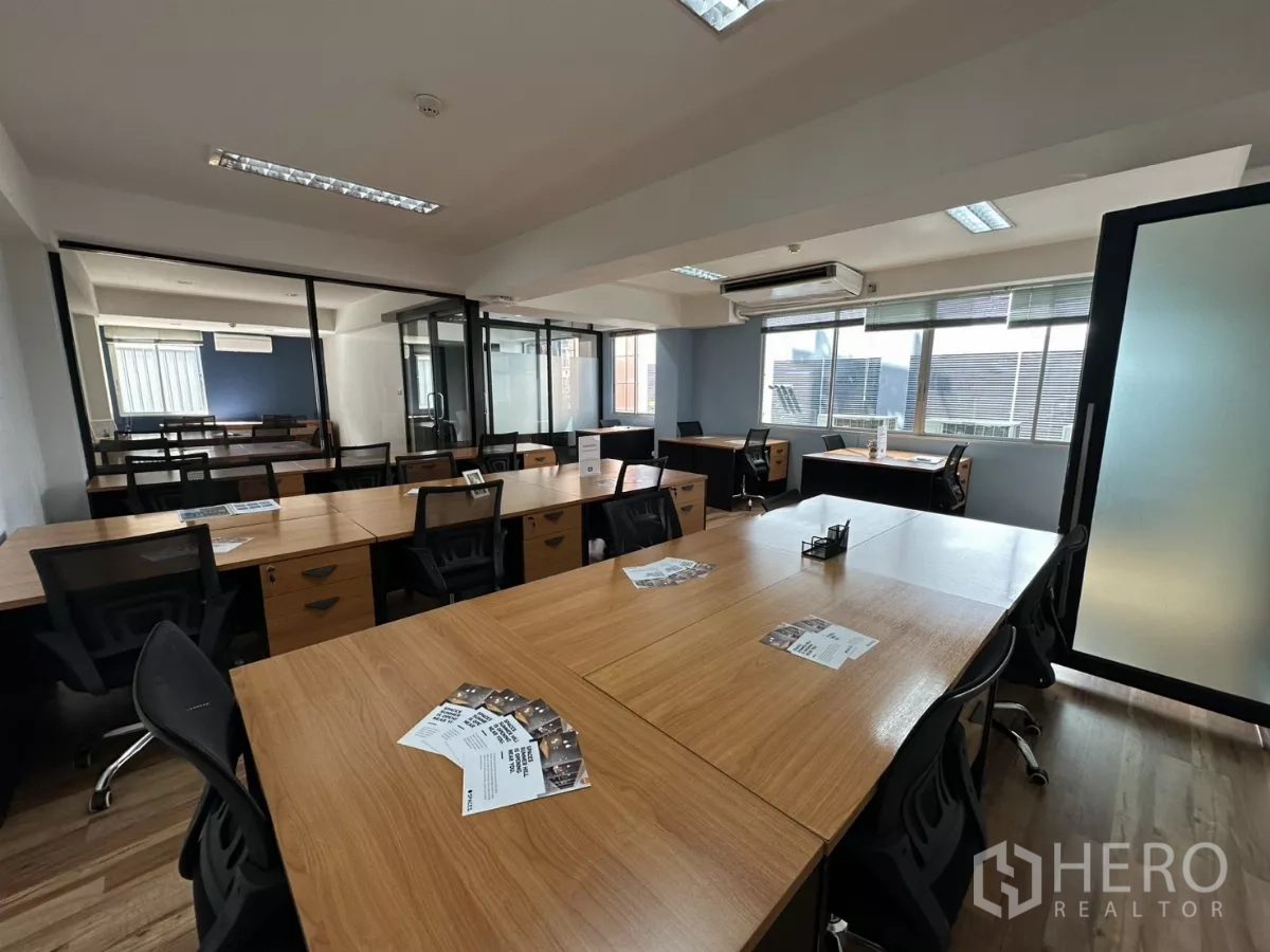 办公空间 出租在Watthana, Bangkok - 中央长桌对着玻璃隔断的私密房间与宽窗的现代办公室。