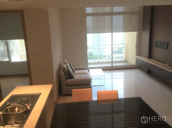 Condominium for rent in Sathon, Bangkok - Bright living room with sofa, built-in TV wall and sliding doors opening to a balcony with city view.