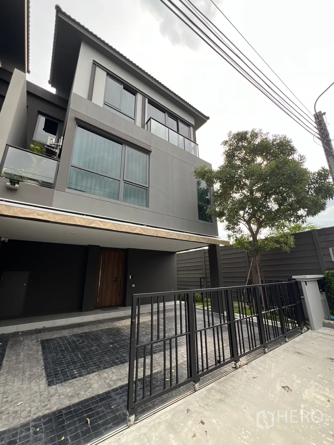 Detached House for rent in Prawet, Bangkok - Angle view of sleek grey exterior and driveway with sliding gate.