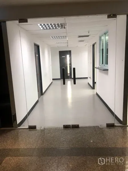 สำนักงาน ให้เช่าในWatthana, Bangkok - ประตูทางเข้ากระจกสู่โถงสำนักงานสว่าง ผนังสีขาวและเสากันผ่าน.