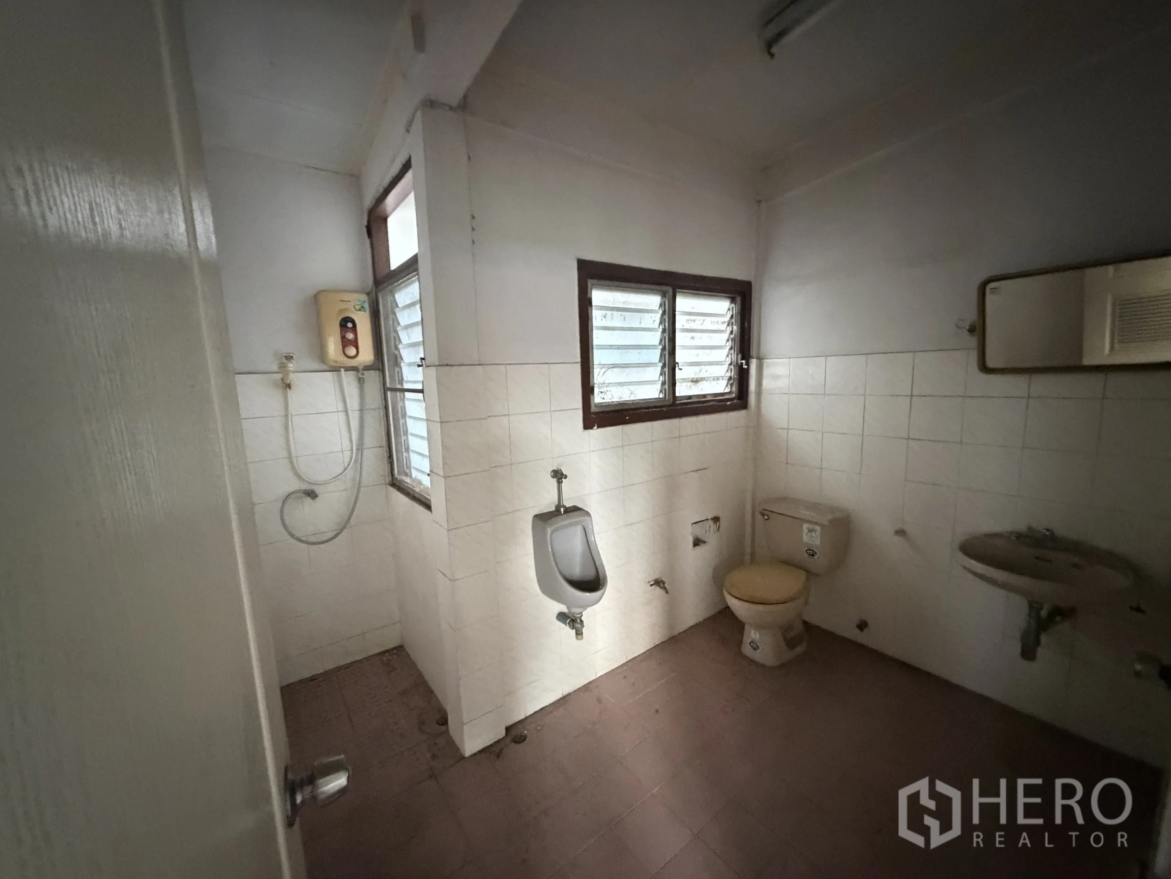 Shophouse for rent in Sathon, Bangkok - Older tiled bathroom with window, water heater, urinal and toilet.