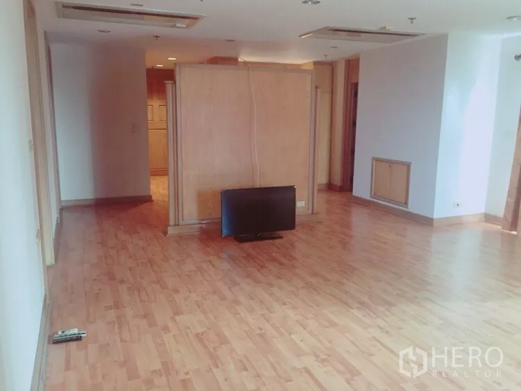 Condominium for rent in Watthana, Bangkok - Empty living area with wood floors and a freestanding TV, ready for décor.