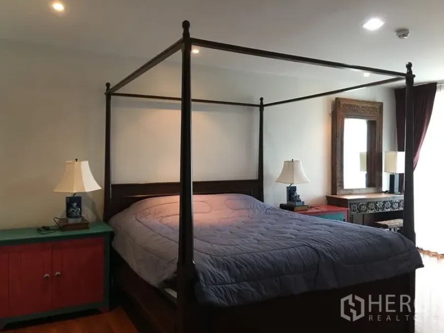 Condominium for rent in Pathum Wan, Bangkok - Master bedroom angle showing four-poster bed, bedside tables, and decorative mirror.