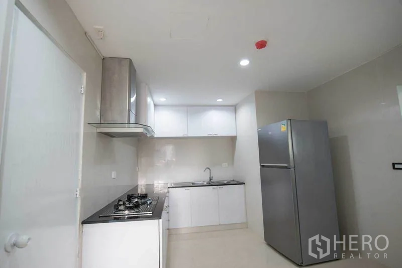 公寓 出租在Khlong Toei, Bangkok - 完整厨房视角，不锈钢冰箱、白色橱柜、水槽与明亮顶灯。