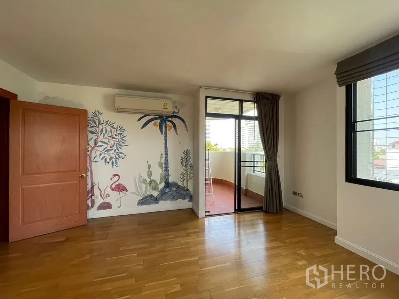 Condominium for rent in Watthana, Bangkok - Spacious bedroom with mural wall, wood flooring and sliding doors to a covered balcony.