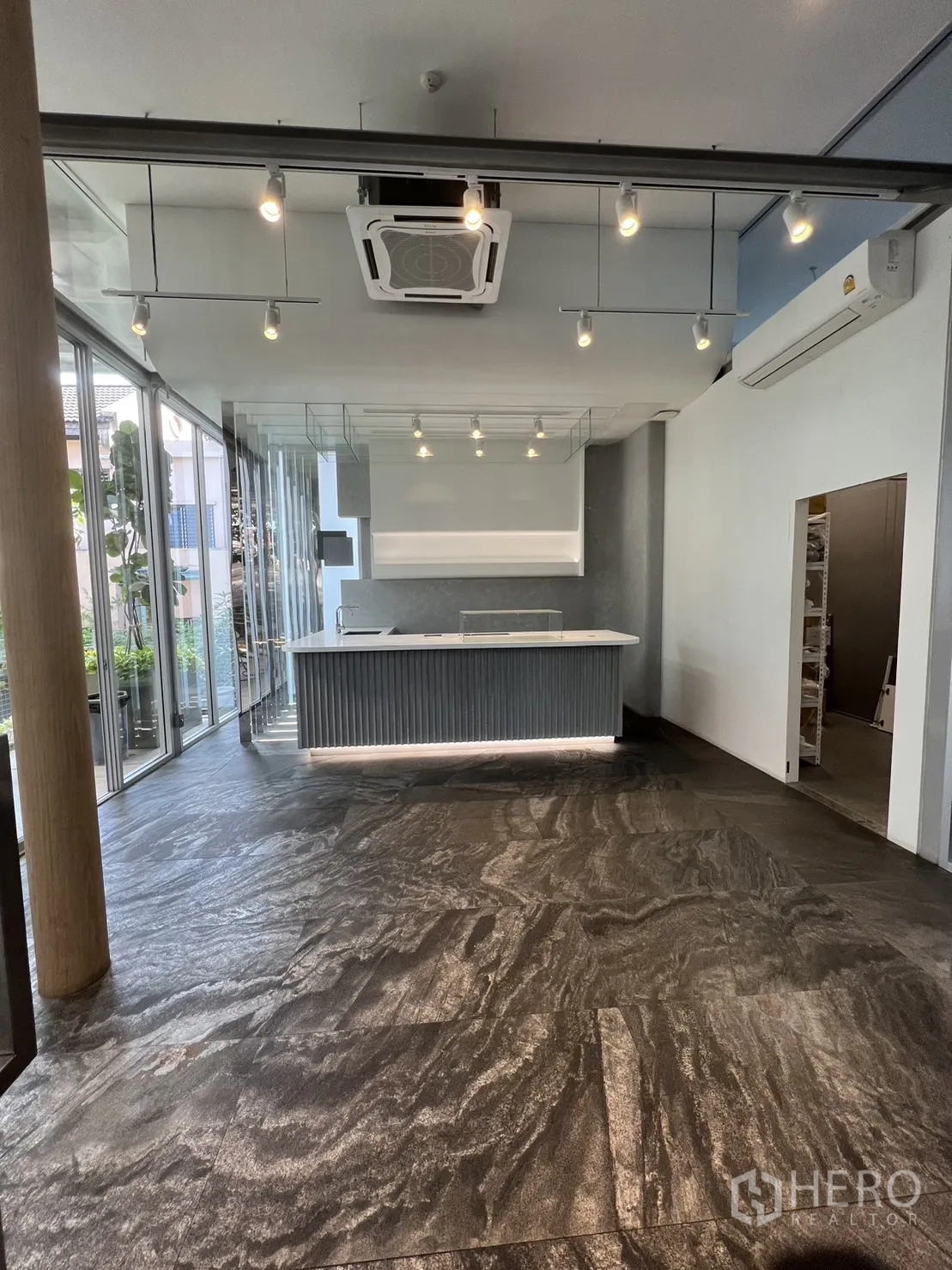 零售空间 出租在Khlong Toei, Bangkok - 明亮的店铺内景，带内置吧台、轨道灯、嵌入式空调与石纹地面，临整面落地玻璃。