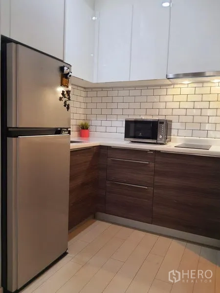 คอนโด ให้เช่าในPathum Wan, Bangkok - ครัวรูปตัวแอลกะทัดรัด ผนังกระเบื้องซับเวย์สีขาว พร้อมตู้เย็นและไมโครเวฟ