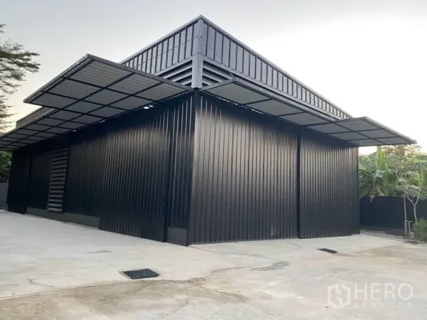 Warehouse for rent in Wang Thonglang, Bangkok - Modern black metal-clad warehouse exterior with large sliding doors and covered loading bays.