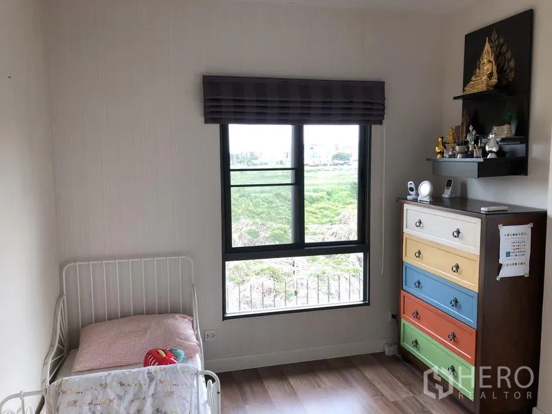 Detached House for rent in Bang Kapi, Bangkok - Cozy child’s bedroom with single bed, colorful dresser, and window with garden view.