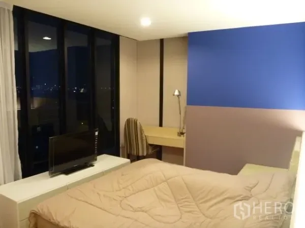 Condominium for rent in Watthana, Bangkok - Master bedroom with city night views, work desk and TV at the foot of the bed.
