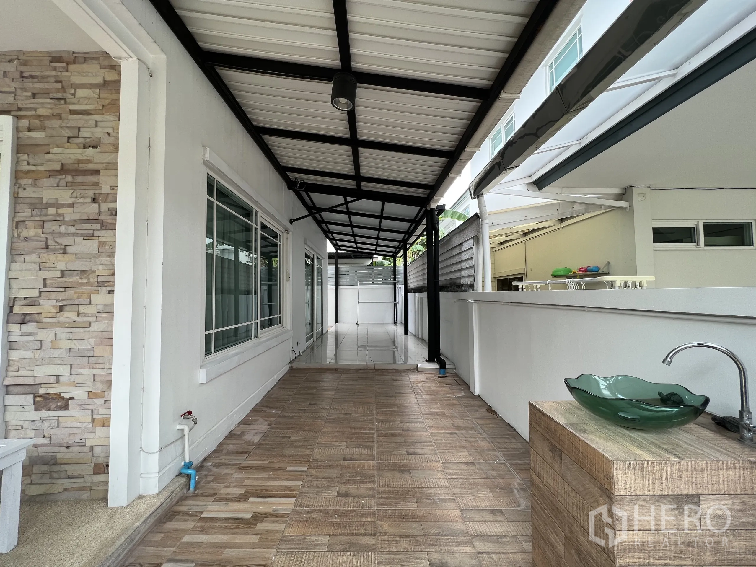 Detached House for rent in Bang Kapi, Bangkok - Covered side patio with a sink, white walls and a metal roof canopy.
