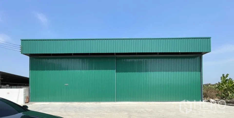 Warehouse for rent in Bang Phli, Samut Prakan - Metal-clad warehouse exterior with large sliding doors and a paved forecourt.