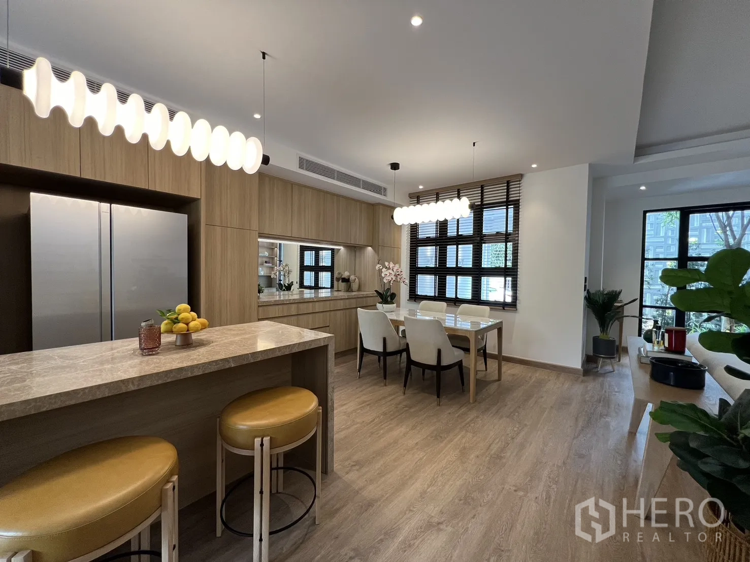 Townhouse for sale in Watthana, Bangkok - Modern kitchen wall with integrated oven, microwave and storage beside the dining area.