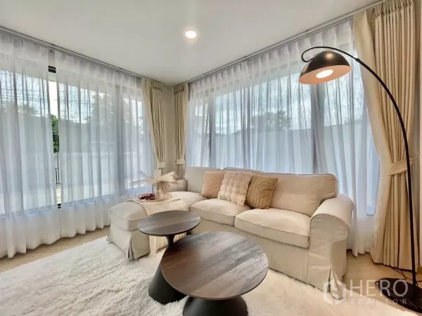 独立式住宅 出售在Prawet, Bangkok - 温馨起居角，落地灯、大面积窗户与柔软地毯。