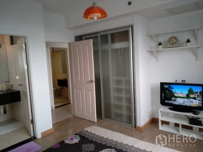 Condominium for rent in Watthana, Bangkok - Bedroom view showing sliding-door closet, wall shelf and small TV stand.