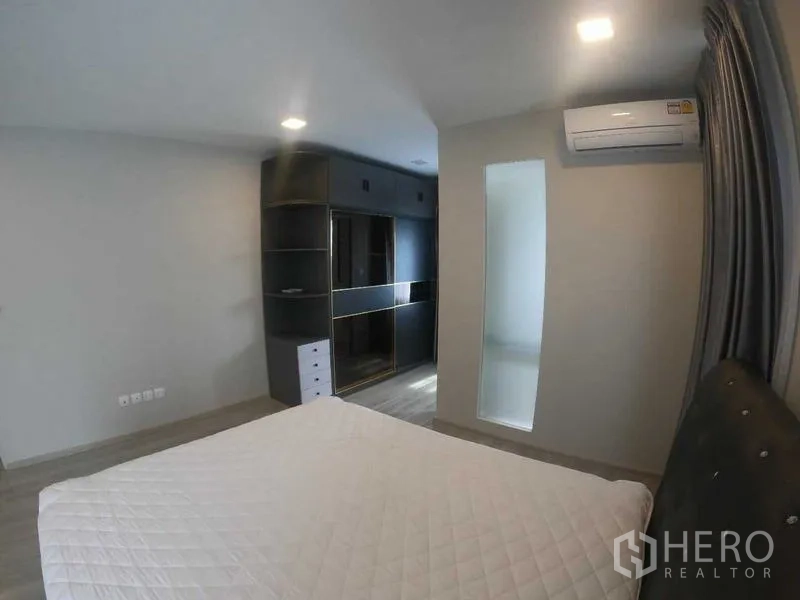 Townhouse for rent - Bedroom fitted with dark built-in wardrobe, drawers, and wall-mounted air conditioner.
