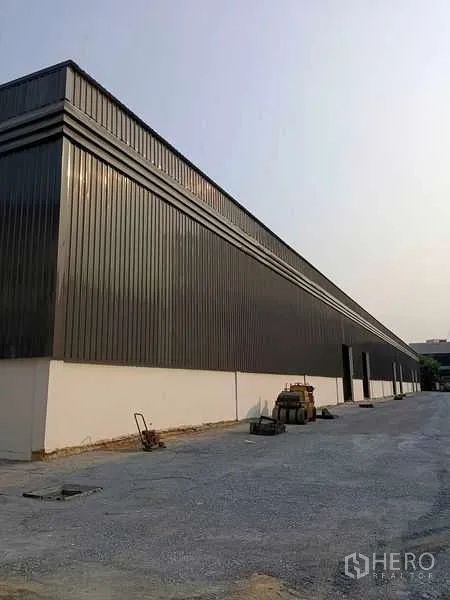 货栈 出租在Khlong Toei, Bangkok - 灰色金属板外立面的大型仓库侧视，场地宽阔