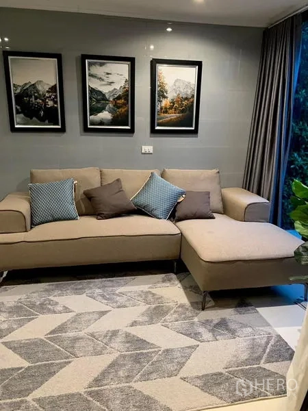 Townhouse for rent in Saphan Sung, Bangkok - Stylish lounge with beige sectional sofa, framed artwork and a large window.