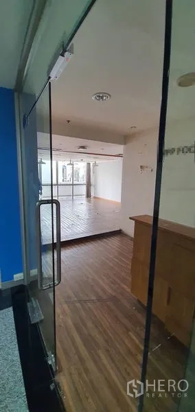 Office Space for rent in Watthana, Bangkok - Entry through a glass door to a bright office with wood floors and a reception counter.
