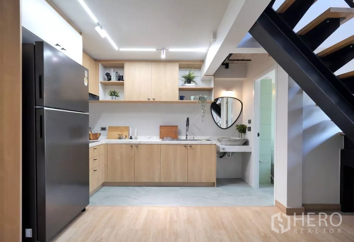 ทาวน์เฮาส์ ให้เช่าในWatthana, Bangkok - ภาพรวมครัวใต้บันได มีชั้นเปิด อ่างล้างจาน และท็อปเคาน์เตอร์ ข้างประตูห้องน้ำ