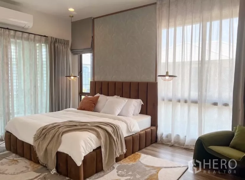 Detached House for rent or sale in Bang Kapi, Bangkok - Master bedroom with upholstered bed, soft lighting, and wide windows with sheer curtains.