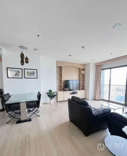 Condominium for sale - Open-plan living and dining area with glass dining table, TV wall unit, and large balcony doors.
