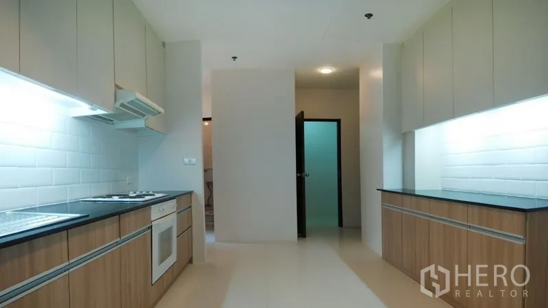 Condominium for rent in Watthana, Bangkok - Large galley kitchen with twin countertops, oven, and white subway-tile backsplash.