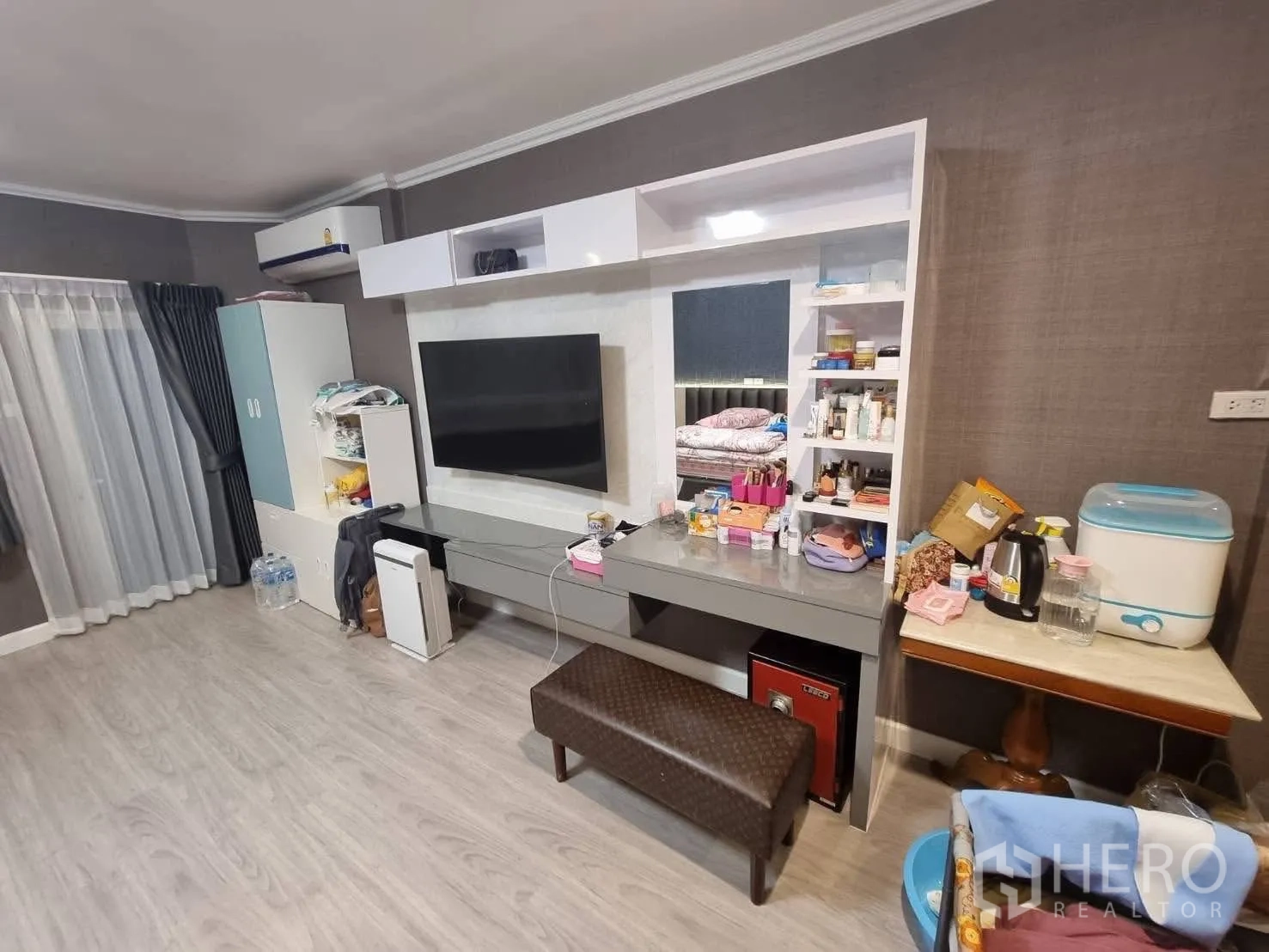 Townhouse for rent in Din Daeng, Bangkok - Built-in TV wall with shelving, vanity desk and storage cabinets.