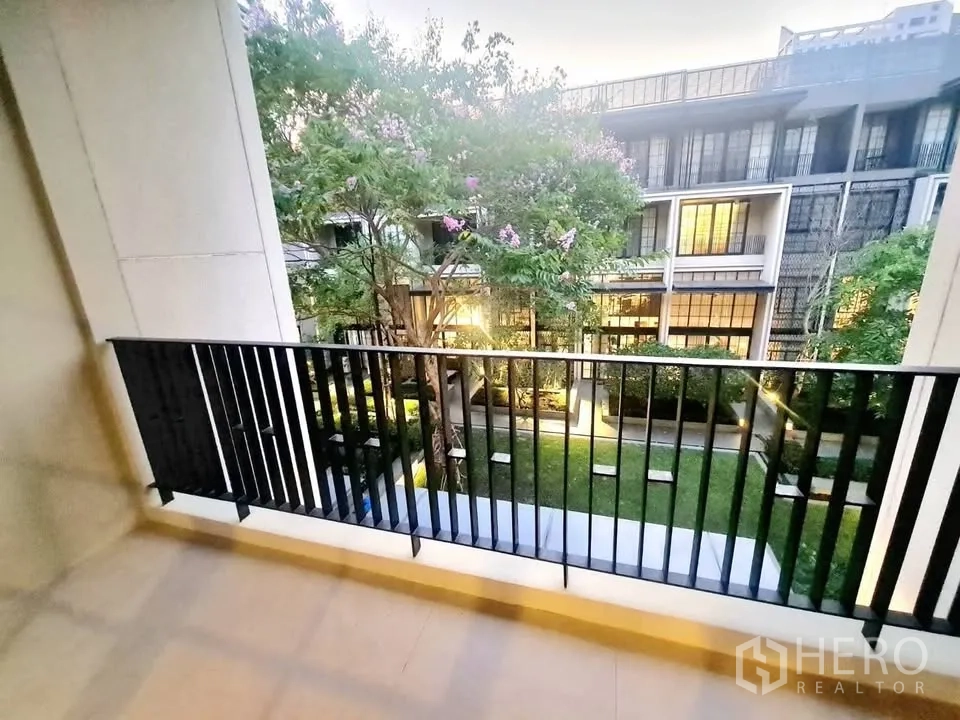 Townhouse for rent or sale in Watthana, Bangkok - Balcony overlooking a landscaped courtyard and modern townhouse facades.
