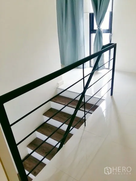 บ้าน ให้เช่าในChok Chai, Nakhon Ratchasima - บันไดลูกนอนไม้ ราวเหล็ก ข้างหน้าต่างสูงพร้อมผ้าม่านสีฟ้า