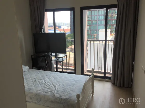 คอนโด ให้เช่าหรือขายในWatthana, Bangkok - ห้องนอนกะทัดรัดพร้อมประตูระเบียงคู่ วิวเมือง โต๊ะวางทีวี และม่านทึบแสง