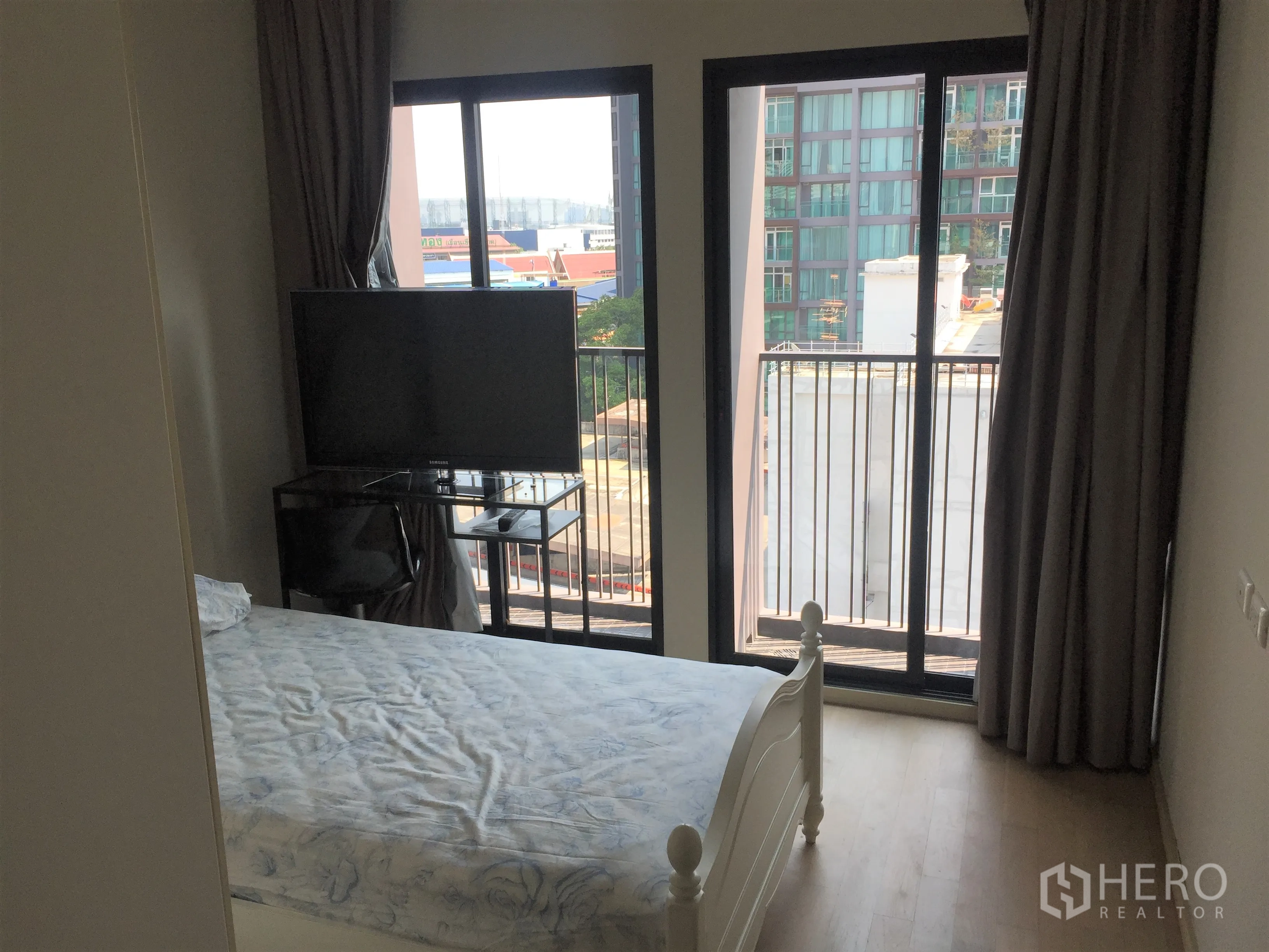 คอนโด ให้เช่าหรือขายในWatthana, Bangkok - ห้องนอนกะทัดรัดพร้อมประตูระเบียงคู่ วิวเมือง โต๊ะวางทีวี และม่านทึบแสง