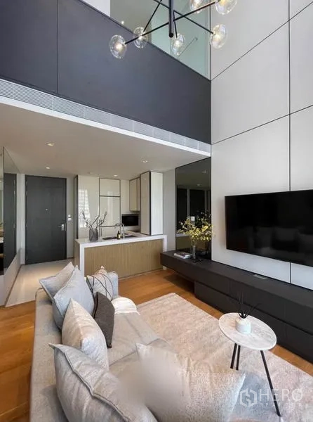 คอนโด ให้เช่าในKhlong Toei, Bangkok - พื้นที่นั่งเล่นใต้ชั้นลอย มีชั้นวางทีวี โซฟา และครัวแบบเปิด