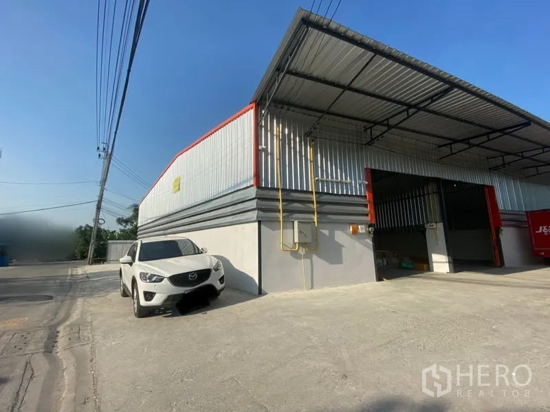 货栈 出租在Lam Luk Ka, Pathum Thani - 金属板外墙仓库，屋顶挑高，带遮棚装卸区、宽幅卷闸门与混凝土前场（Lam Luk Ka）。