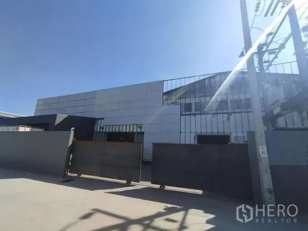 โรงงาน ขายในSaphan Sung, Bangkok - ด้านหน้าตัวอาคารอุตสาหกรรม พร้อมประตูเหล็กบานเลื่อนและช่องแสง ใต้ท้องฟ้าโปร่ง