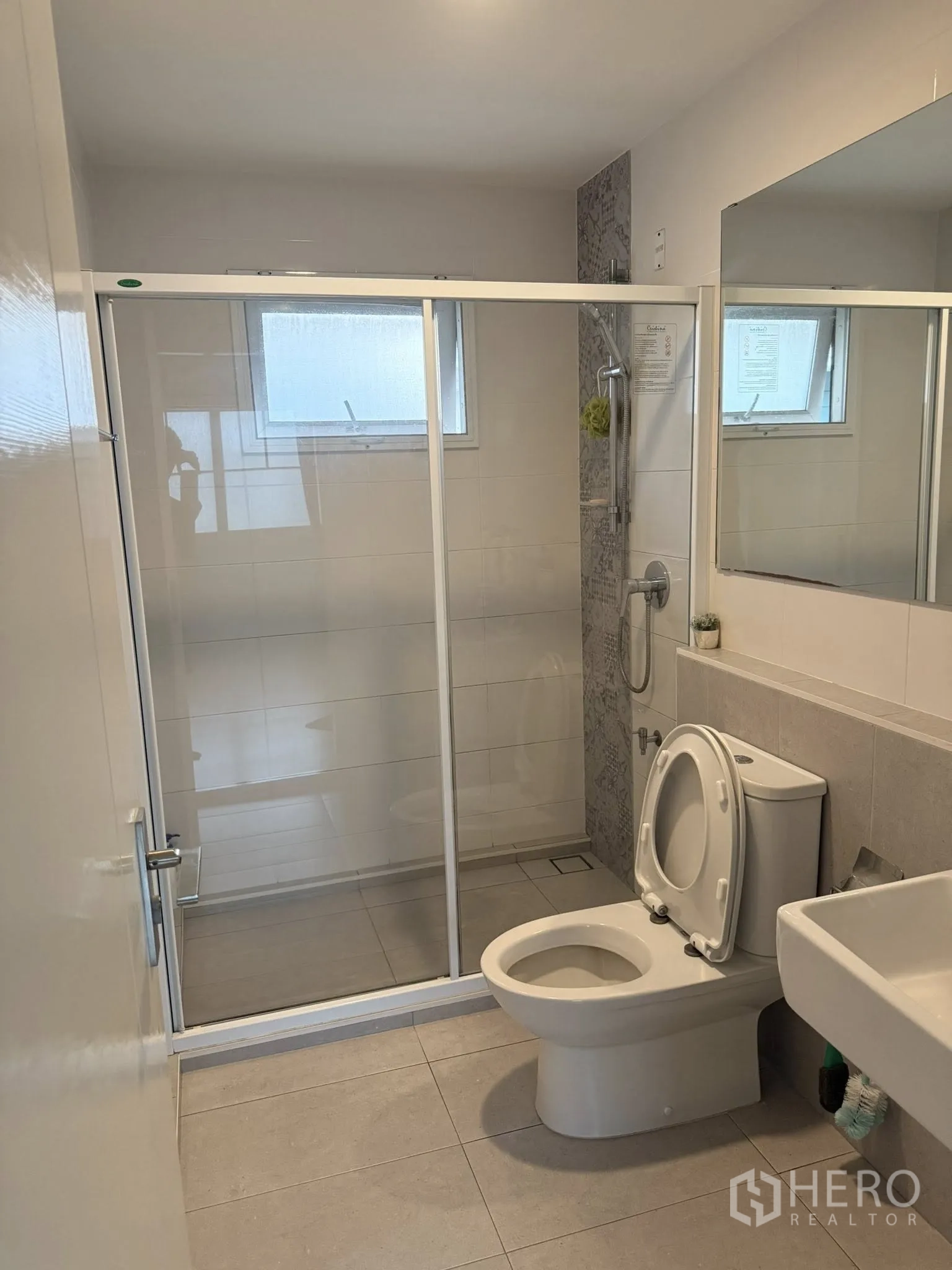 Townhouse for rent or sale in Sai Mai, Bangkok - Clean bathroom with glass-enclosed shower, toilet and wall mirror.