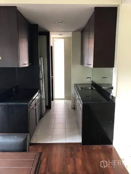 บ้าน ขายในWang Thonglang, Bangkok - ครัวแบบแกลเลอรี ตู้สีเข้ม เคาน์เตอร์หินสีดำ และอ่างล้างจานสองหลุม.