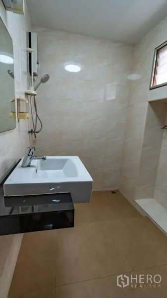 Townhouse for rent in Khlong Toei, Bangkok - Modern bathroom with walk‑in shower, beige tiles and wall‑mounted sink.