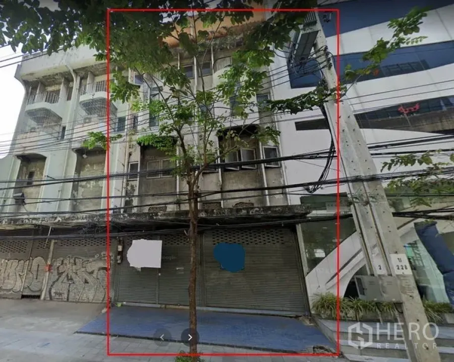 店屋 出租在Bang Na, Bangkok - 临街多层店屋外立面，金属卷闸门、人行道与电线可见