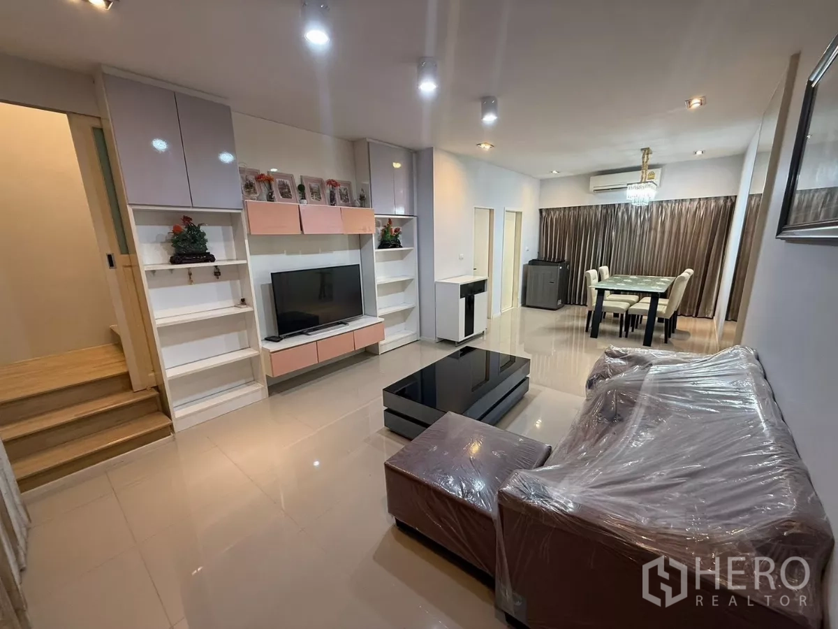 ทาวน์เฮาส์ ให้เช่าในSuan Luang, Bangkok - พื้นที่รับแขกและทานอาหารแบบโอเพ่น พร้อมผนังบิลท์อินทีวี พื้นเงา และโซฟา