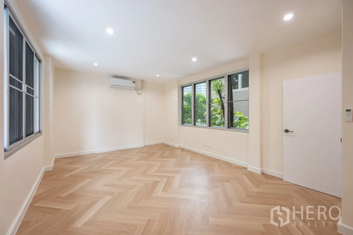 Detached House for rent or sale in Chatuchak, Bangkok - Spacious bedroom with herringbone floor, multiple windows, and split air conditioner.