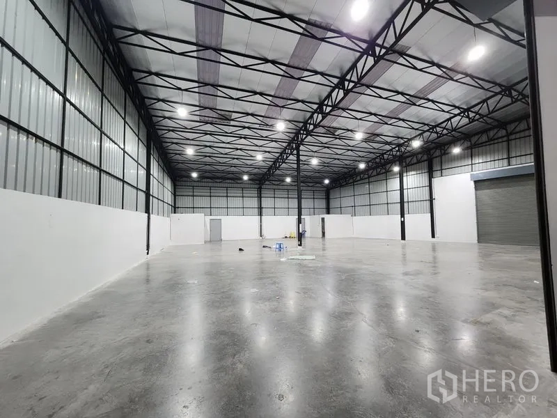 Warehouse for rent in Pak Kret, Nonthaburi - Wide open warehouse floor with bright lighting, good ventilation and service doors along the back wall.