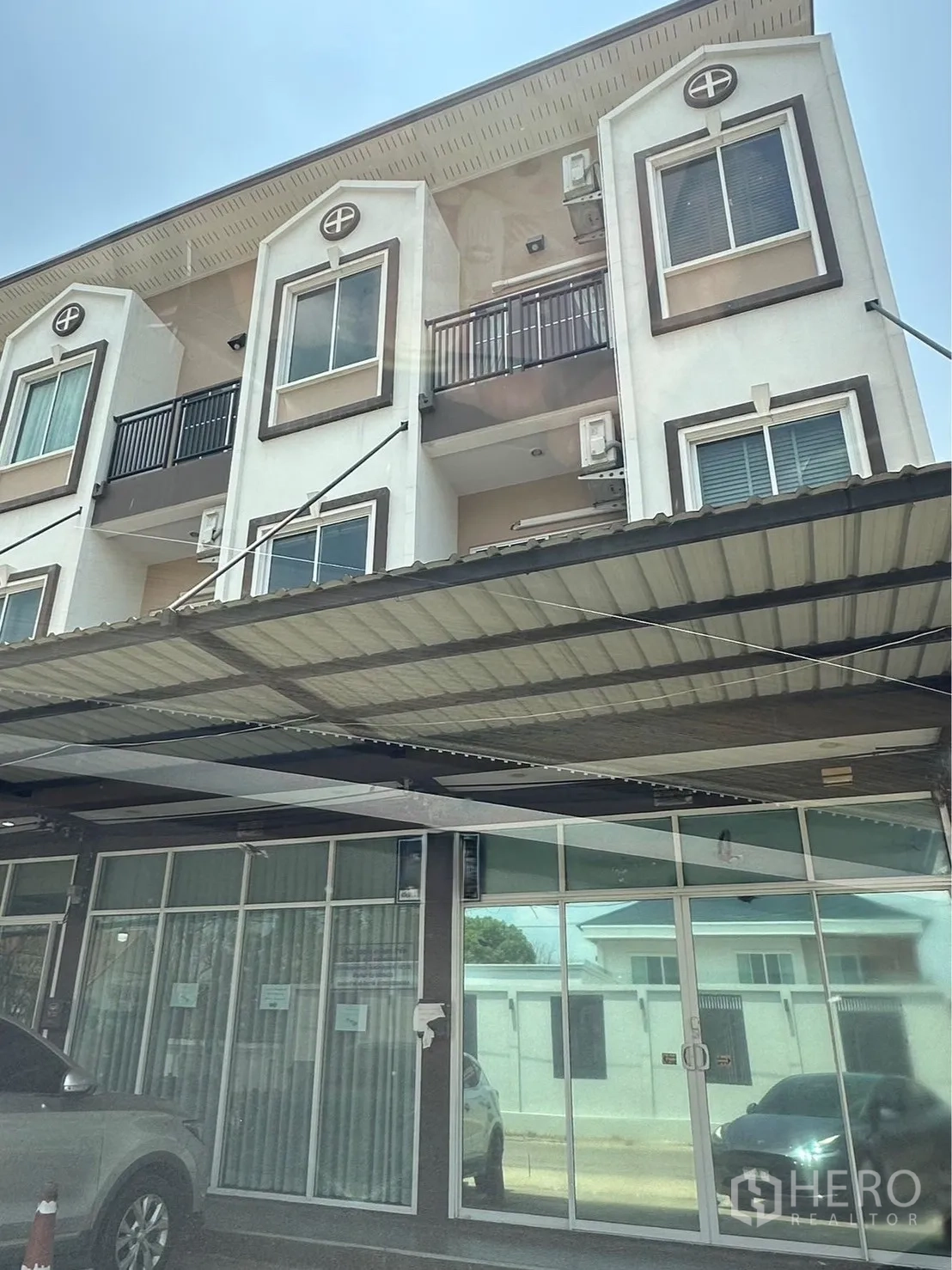 Home Office for rent in Khlong Luang, Pathum Thani - Three-storey home office exterior with balconies, air conditioners and a glass-fronted ground floor under a large awning.