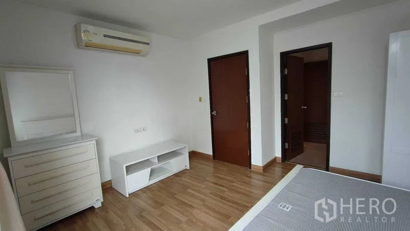 คอนโด ให้เช่าในKhlong Toei, Bangkok - มุมห้องนอนพร้อมตู้ลิ้นชัก ชั้นวางทีวี เครื่องปรับอากาศ และประตูสองบาน พื้นไม้